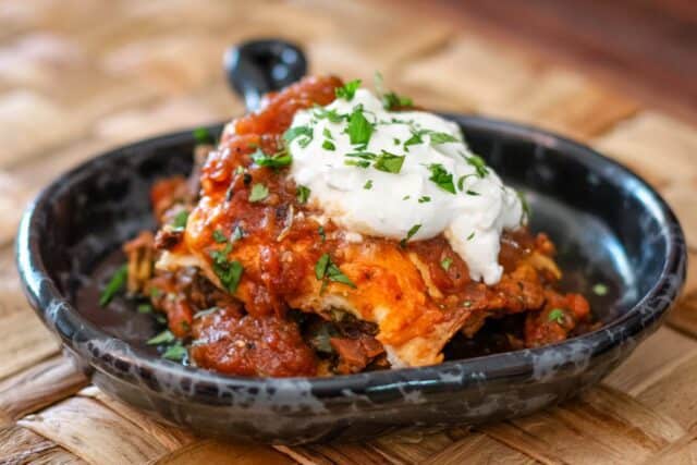 Burrito bake in a serving dish with sour cream and cilantro.