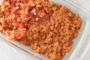 Burrito casserole preparation with refried beans and salsa.