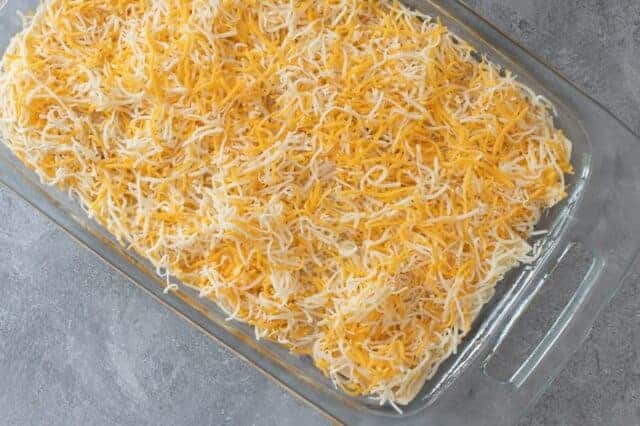 Burrito casserole preparation with cheese topping.