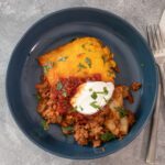 burrito casserole on a plate with sour cream and cilantro