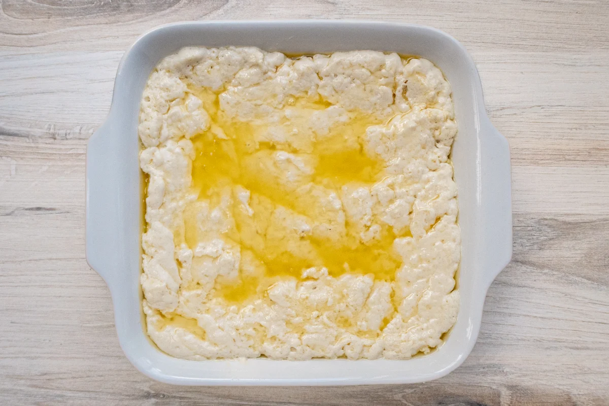 Butter and biscuit batter spread in the baking dish.