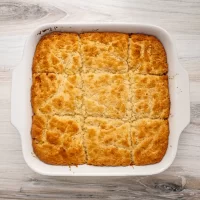 Golden baked dessert with a crumbly topping in a white casserole dish.