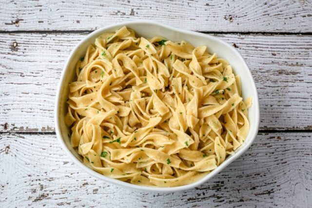 buttered noodles with parsley in a serving bowl