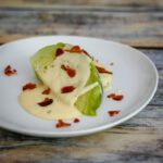 cooked cabbage wedge with cheese sauce and bacon on a plate