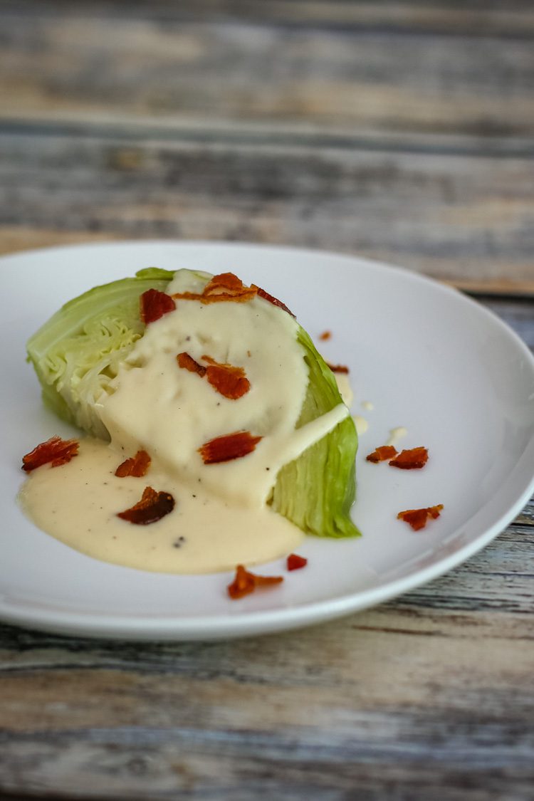 wedge of cabbage on a plate with cheese sauce bacon