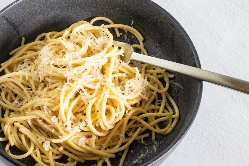 cacio e pepe pasta with spaghetti and extra pecorino, in a bowl.