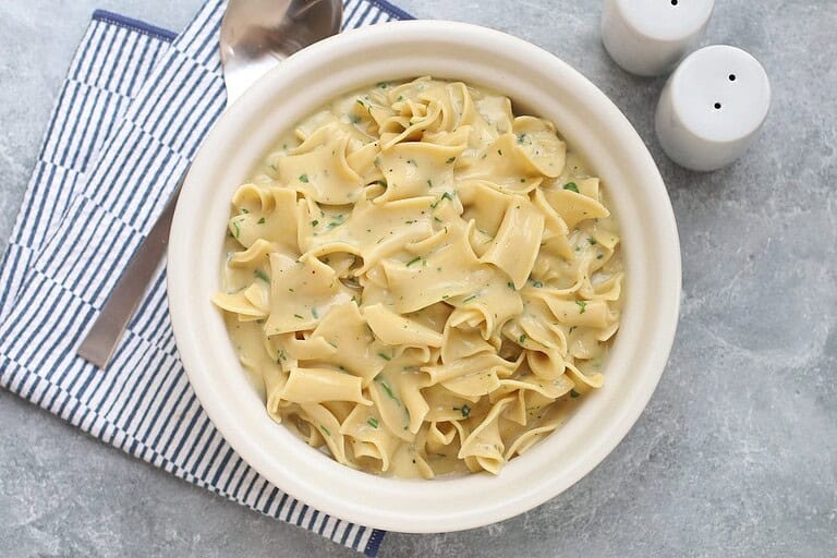 Creamy pasta with herbs in a white bowl.