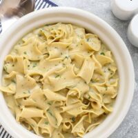 Creamy herb pasta in a white bowl on gray surface.
