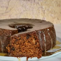 Rich chocolate carrot cake with glazed topping and sliced piece.