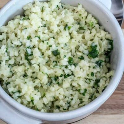 A bowl of cauliflower rice with garlic, parmesan cheese, and parsley