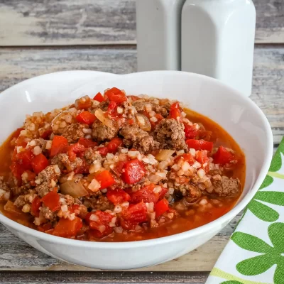 Rich beef and vegetable stew in a white bowl on a rustic wooden table.