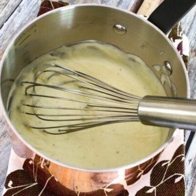 cheese sauce in a copper pan with whisk