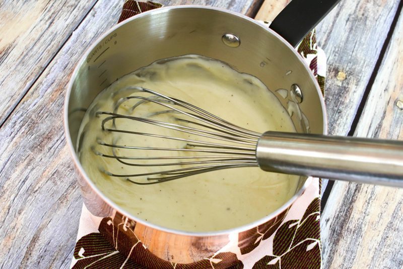 cheese sauce in a copper pan with whisk