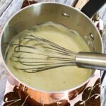 making cheddar cheese sauce with a saucepan and whisk