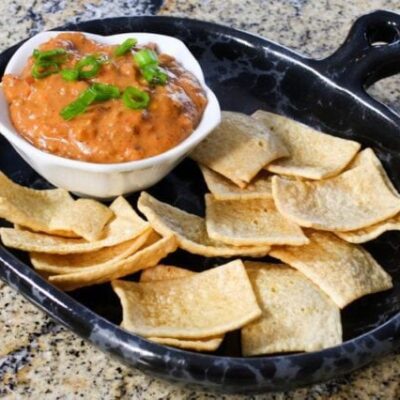 chili cheese dip with sausage on a plate with chips