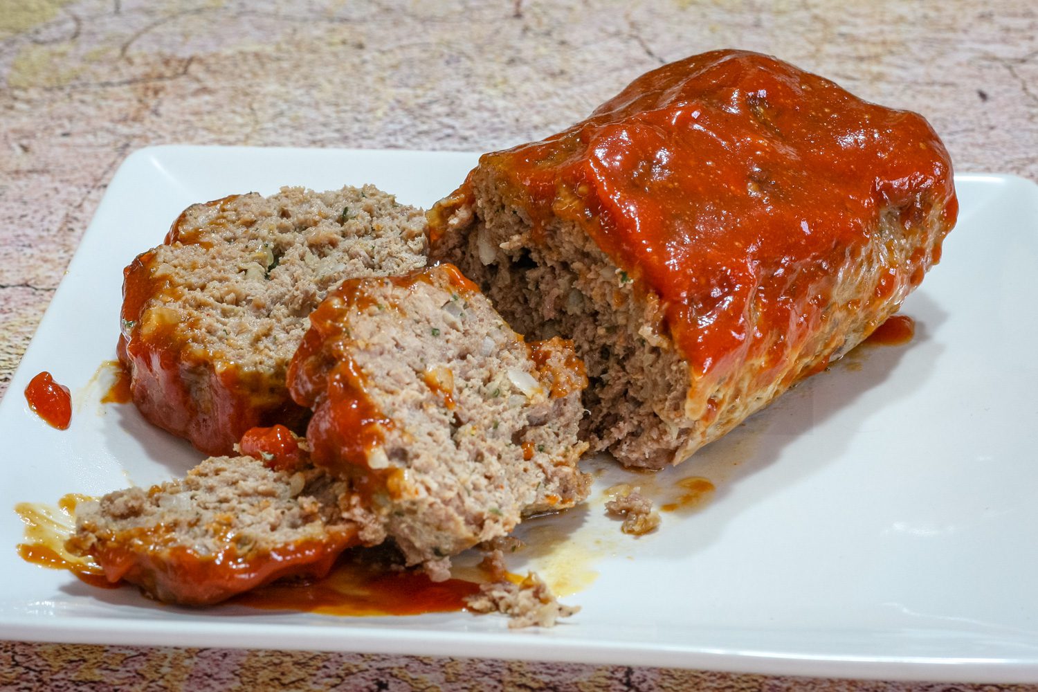 A tasty loaf of cheddar and tomato soup meatloaf on a platter, sliced.