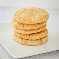 Soft, golden oatmeal cookies stacked on a white plate.
