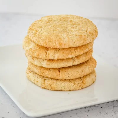 Soft, golden oatmeal cookies stacked on a white plate.