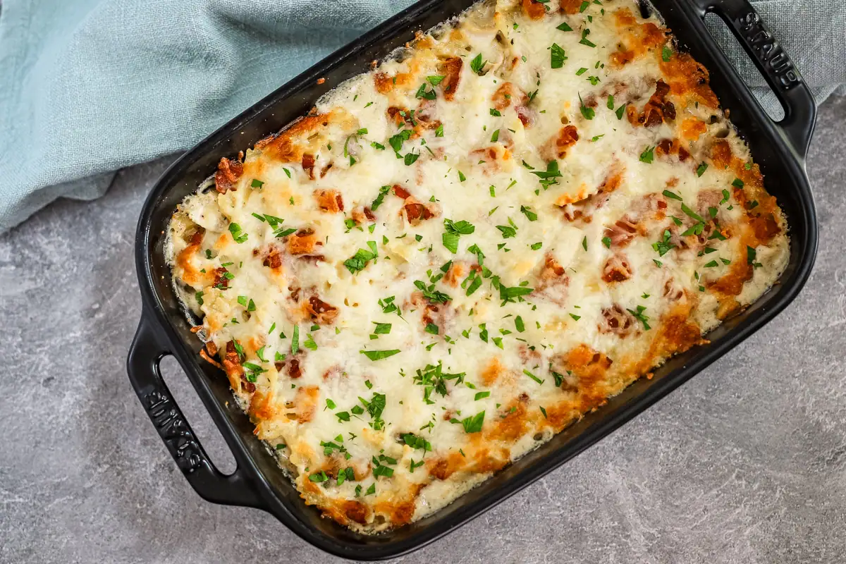 A baking dish with chicken bacon ranch pasta casserole garnished with parsley.