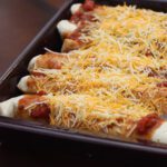 a baking dish with chicken enchiladas topped with cheese