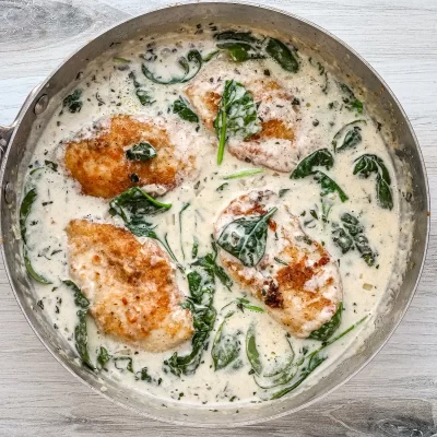 Baked chicken breasts simmering in a creamy spinach sauce.