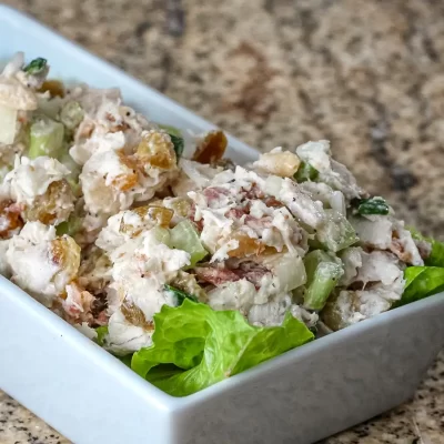 Creamy chicken salad with celery and lettuce in a white dish.