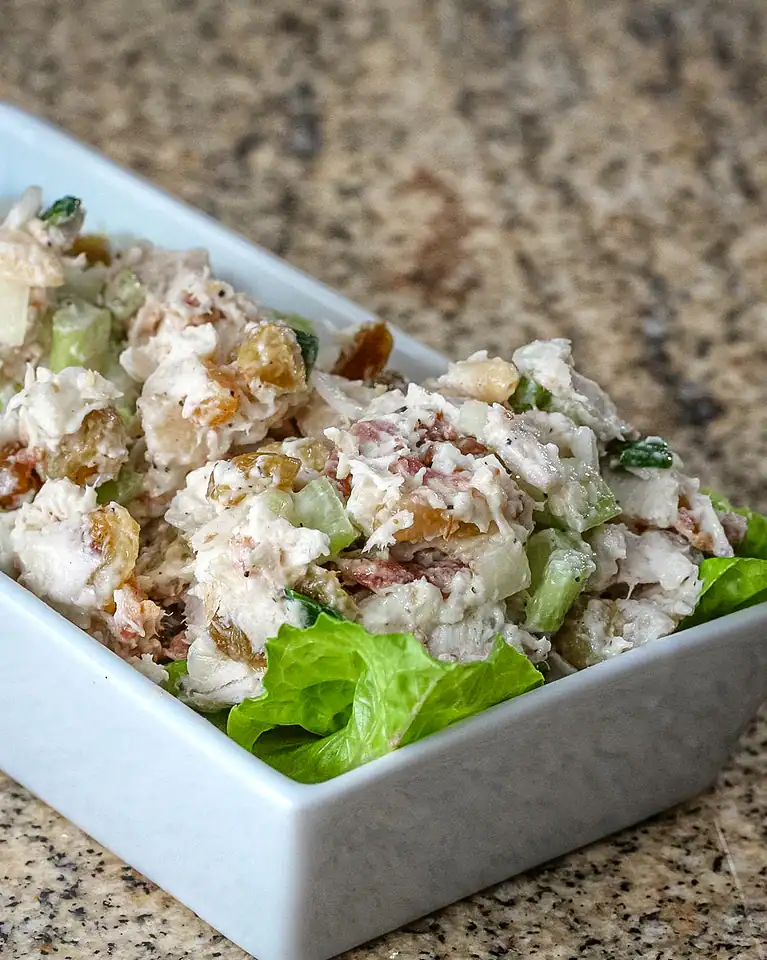 Creamy chicken salad with celery and lettuce in a white dish.