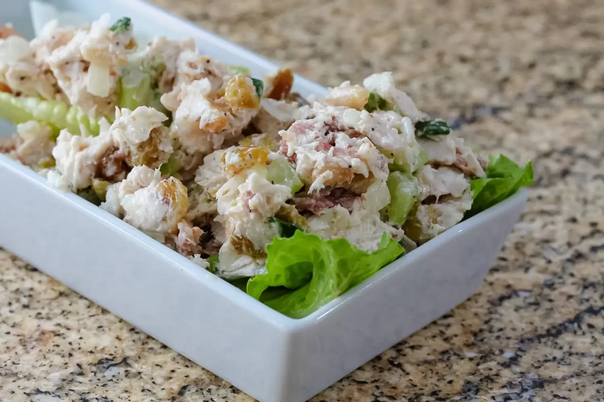 Creamy chicken salad with celery and grapes served in a white dish.
