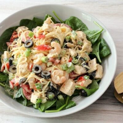 chicken and shrimp pasta salad with angel hair pasta and olives, in a serving dish