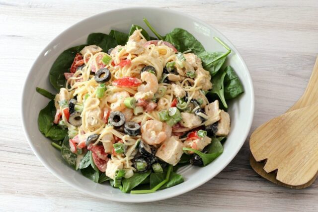 chicken and shrimp pasta salad with angel hair pasta and olives, in a serving dish