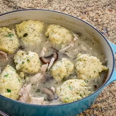 Savory chicken and dumplings simmering in a flavorful broth with mushrooms and herbs.