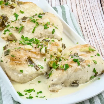 Baked chicken breasts topped with creamy sauce and green onions.