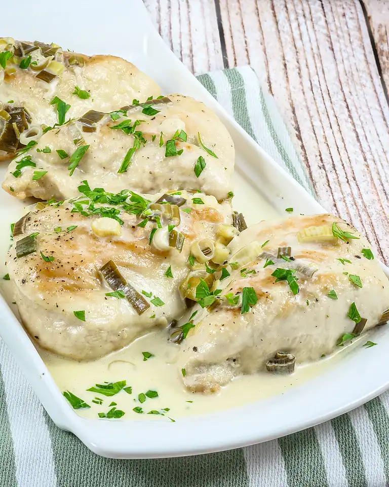 Baked chicken breasts topped with creamy sauce and green onions.