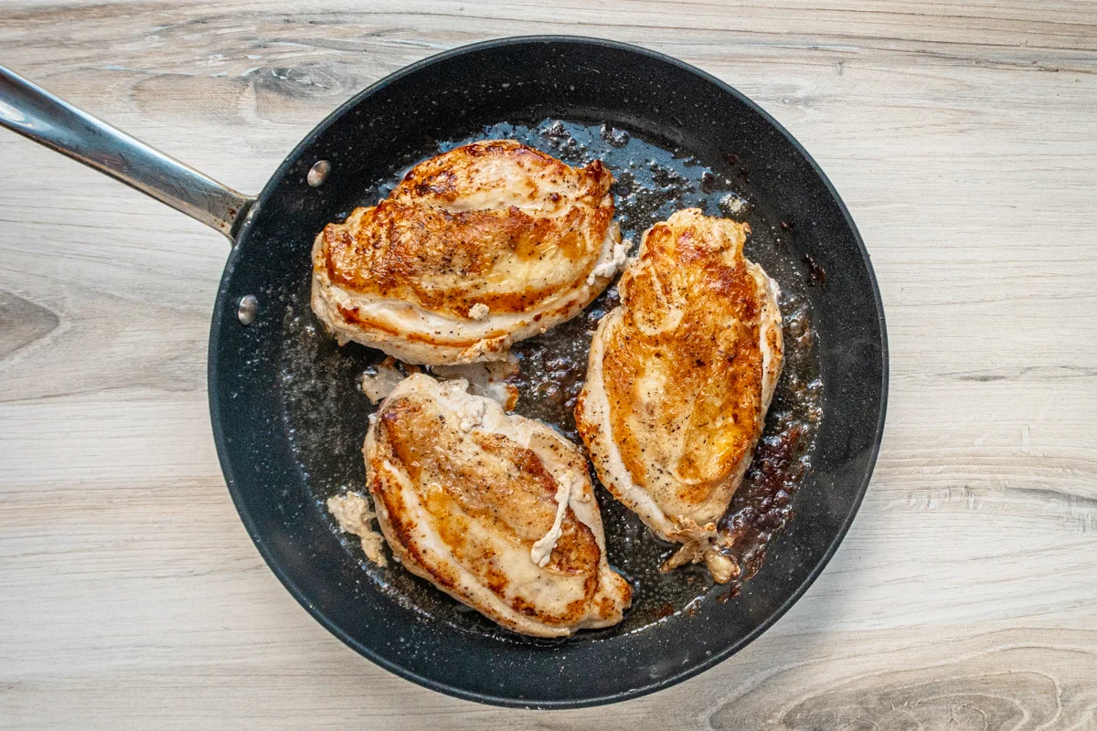 Seared boneless chicken breasts in the skillet.