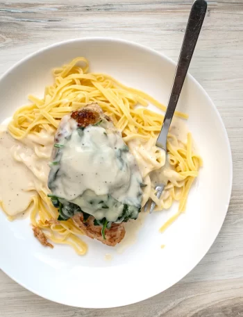 Chicken breasts with a topping of wilted spinach and melted Gruyère cheese on pasta with a creamy white wine and Parmesan cheese sauce.