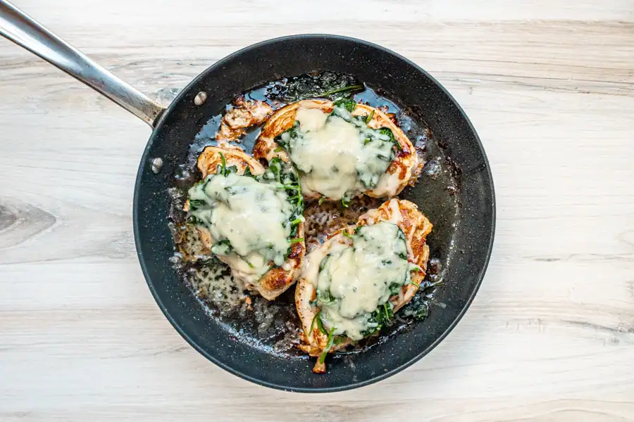 Baked chicken breasts topped with melted cheese and herbs.