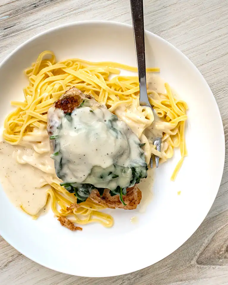 Creamy chicken and spinach stuffed on a bed of cooked spaghetti.