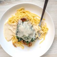 Creamy chicken Parmesan over spaghetti with melted cheese and sauce.