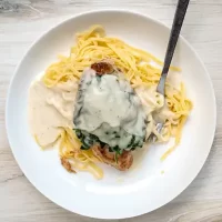 Creamy spinach and cheese topping on pasta dish.