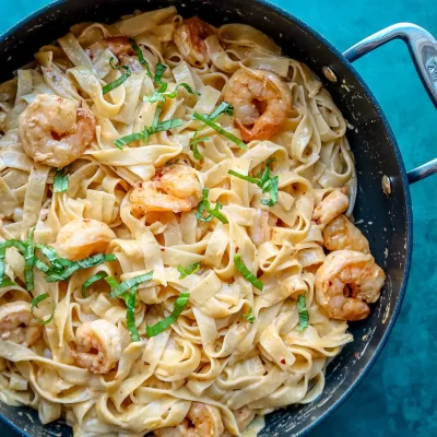 Creamy shrimp pasta in a black skillet.