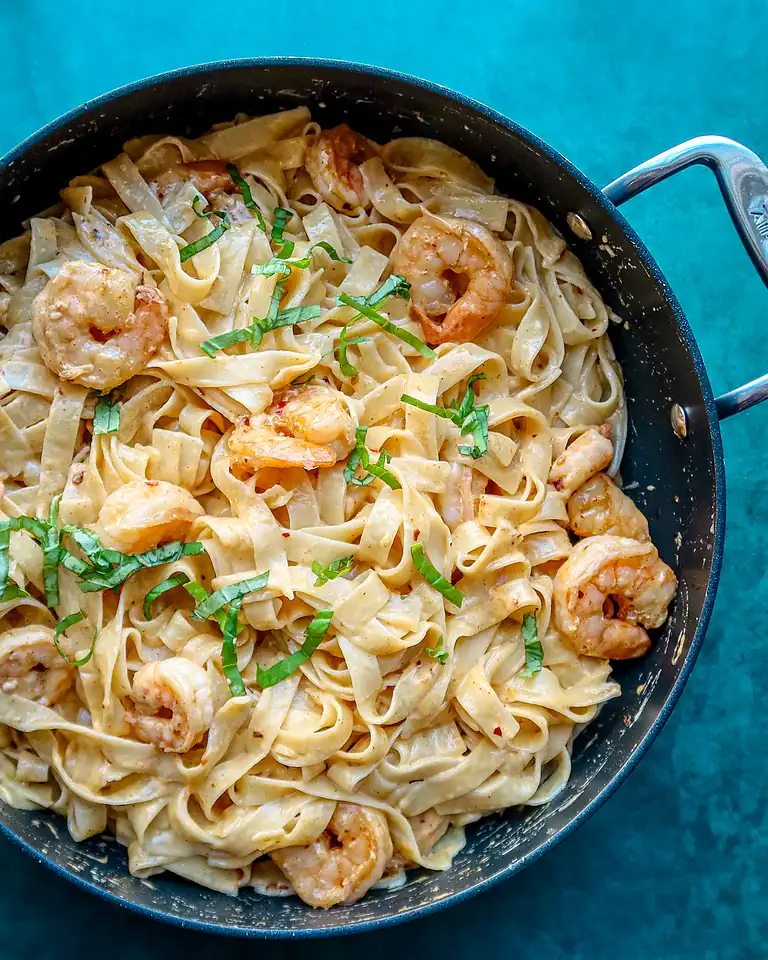Creamy shrimp pasta in a black skillet.