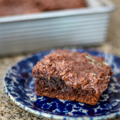Chocolate buttermilk cake with chocolate frosting on a blue pottery plate.