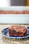 Fudgy chocolate brownie with nut topping on a blue and white plate.