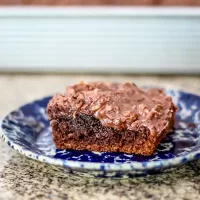 Delicious chocolate brownie with nuts on blue patterned plate.