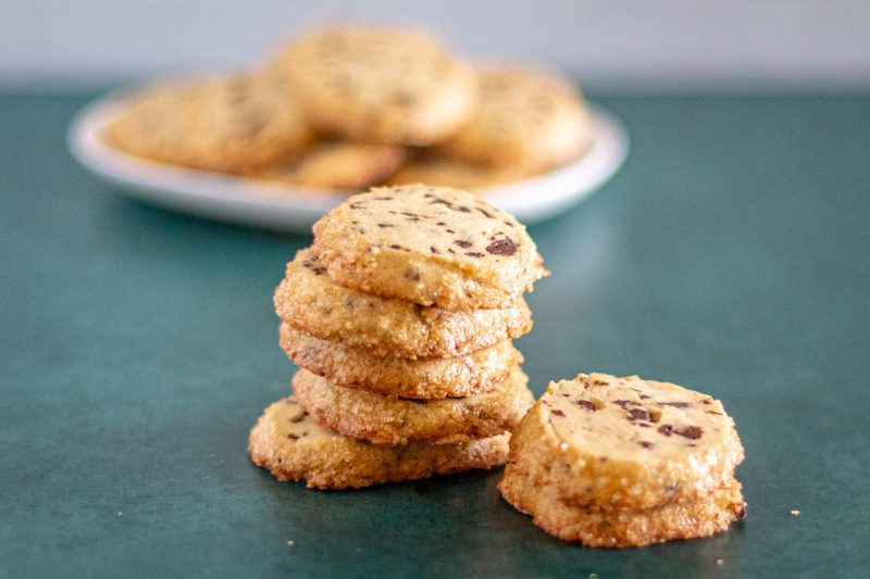 A stack of chocolate chip sablé cookie showing the sugary edges.