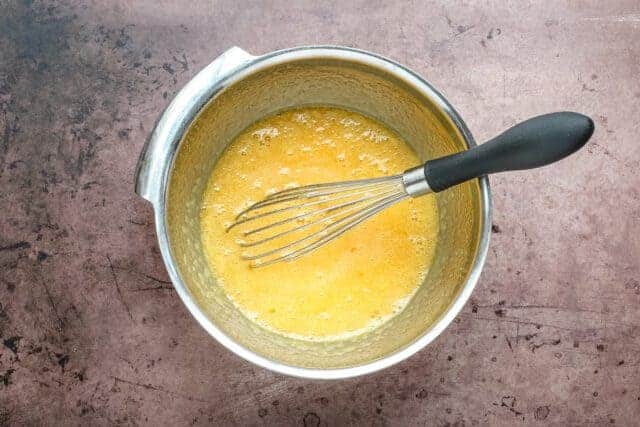 Frying pan with whisk and scrambled eggs.