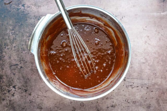 Smooth chocolate mixture in a mixing bowl with a whisk inside.
