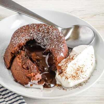 Warm molten chocolate lava cake with a gooey center and whipped cream on the side.
