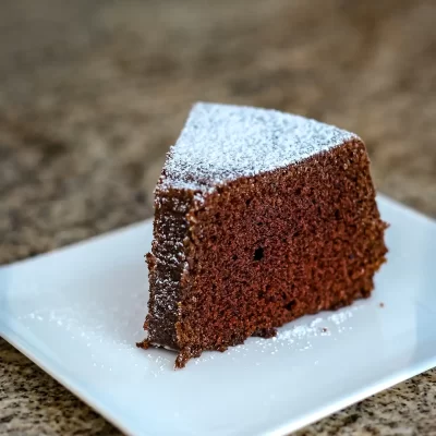 Rich chocolate cake sliced and dusted with powdered sugar in close-up.
