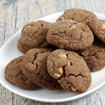 Fudgy chocolate cookies with chopped nuts on white plate.